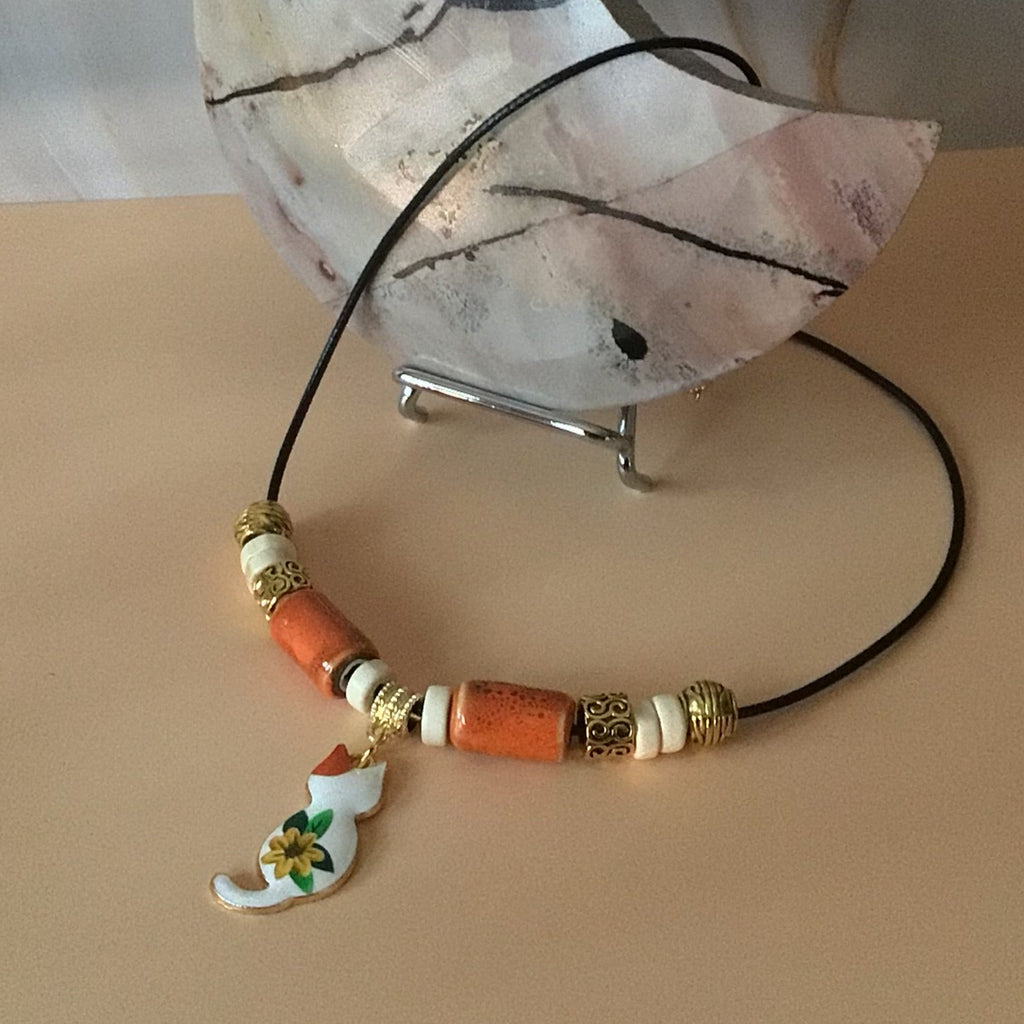 Necklace with decorative beads and cat charm on a beige background